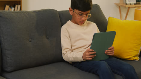Kleiner-Junge-Sitzt-Zu-Hause-Auf-Dem-Sofa-Und-Spielt-Spiele-Oder-Streamt-Auf-Ein-Digitales-Tablet-2